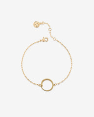 Gold bracelet with a circular charm on a white background