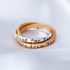 Three stacked rings with engraved text on a light gray background