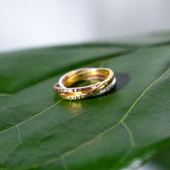 Three gold rings stacked on a green leaf